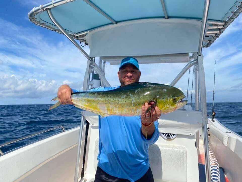 Man proudly holding a freshly caught fish on a boat, only available at Salty Dog Fishing Charters-Johns Pass-Treasure Island.