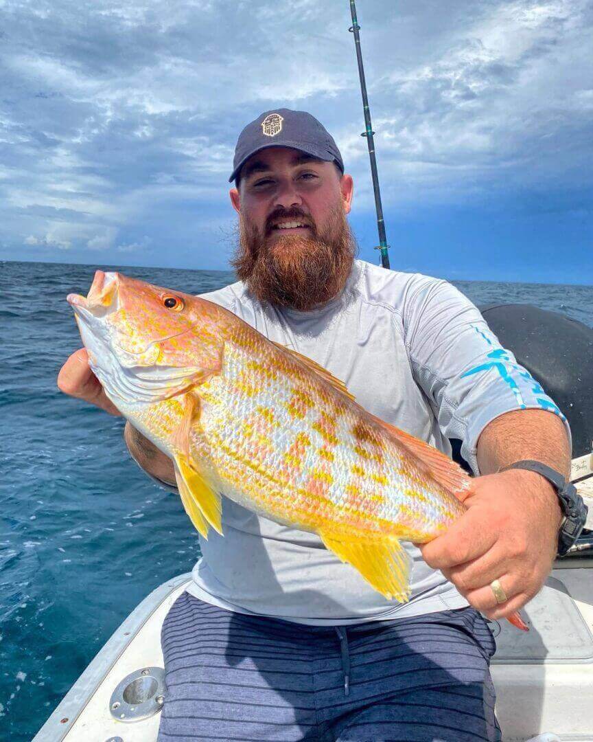 Angler proudly holding a vibrant yellow fish on a boat, only available at Salty Dog Fishing Charters-Johns Pass-Treasure Island.
