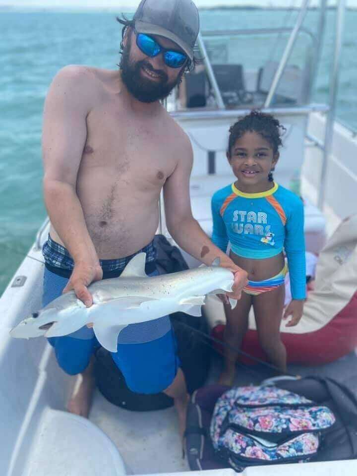Man and child holding a fish on a boat, enjoying a fishing trip with Salty Dog Fishing Charters-Johns Pass-Treasure Island.