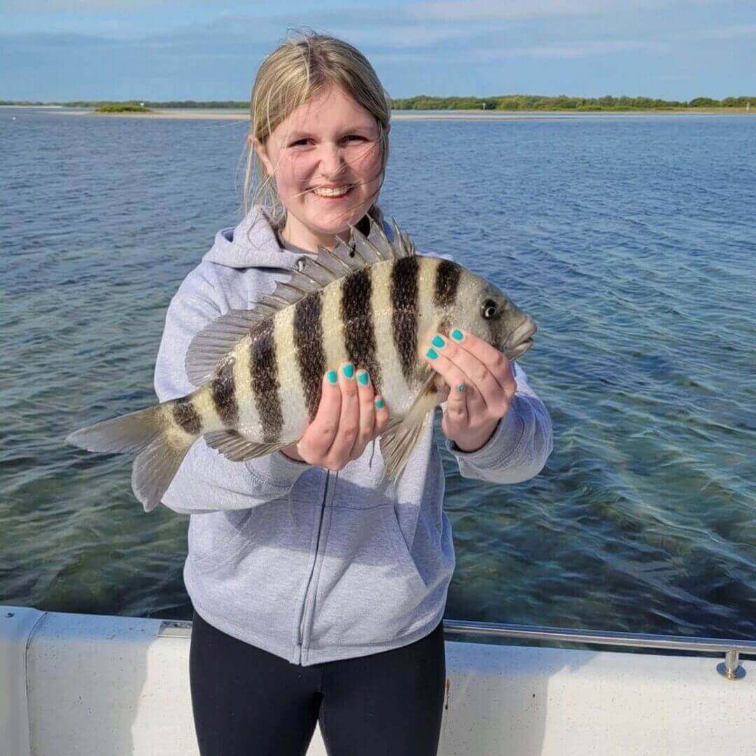 Young angler holding a fish on a scenic boat trip, only available at Salty Dog Fishing Charters-Johns Pass-Treasure Island.