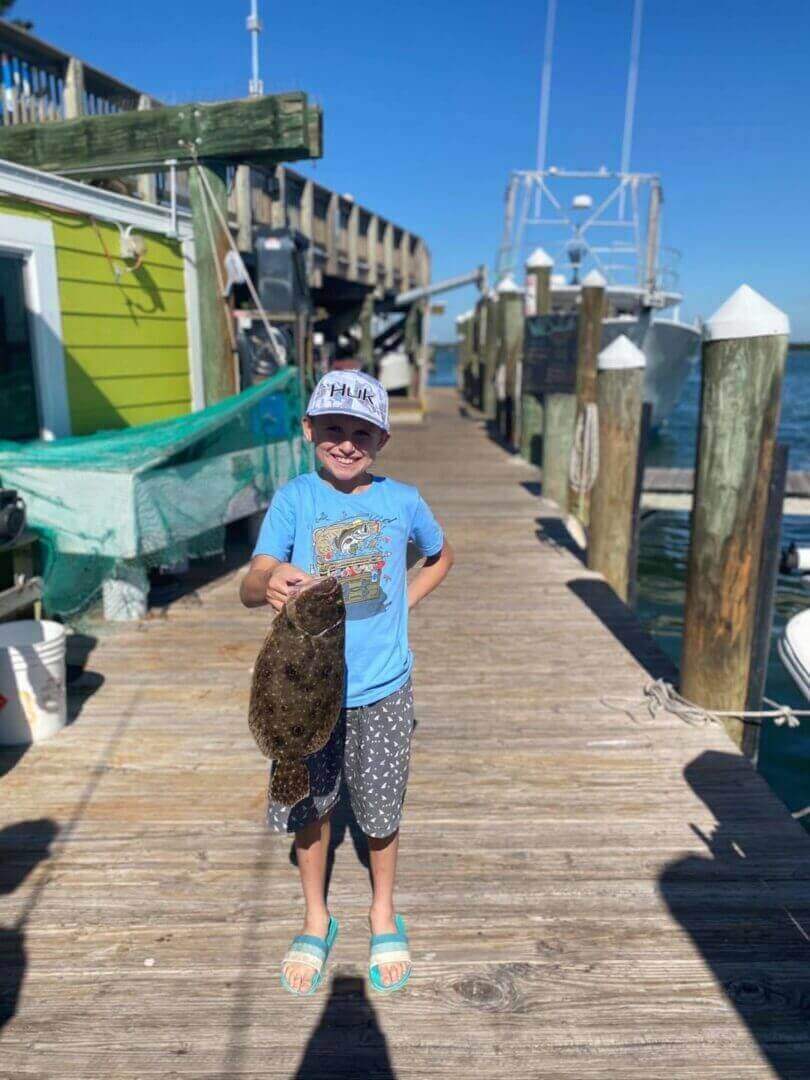 Young angler with a catch on dock, only at Salty Dog Fishing Charters-Johns Pass-Treasure Island.
