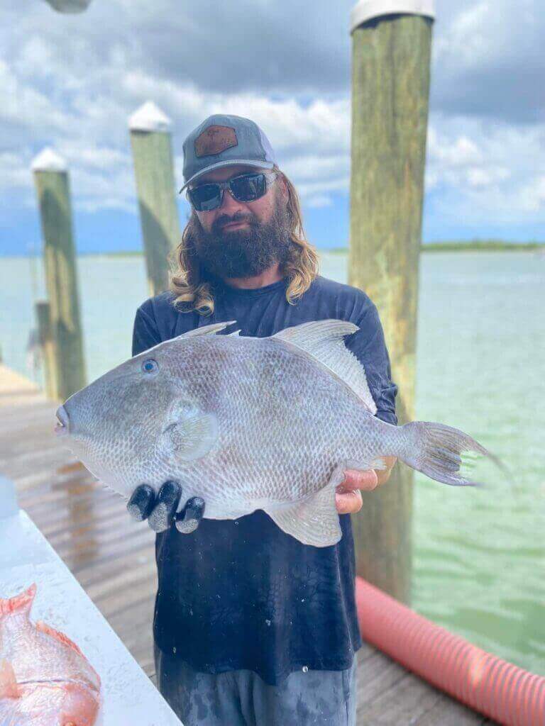 Angler holding a large fish on the dock, showcasing a successful catch with Salty Dog Fishing Charters-Johns Pass-Treasure Island.
