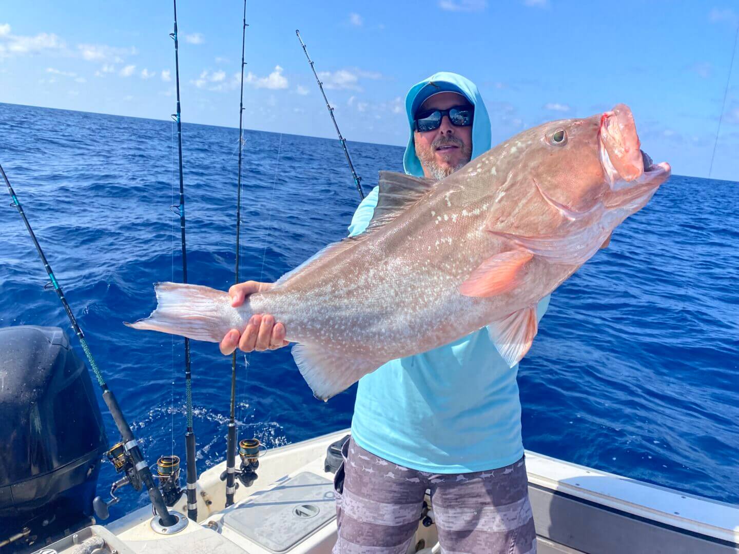 Angler holding a large fish on a boat under clear skies, only available at Salty Dog Fishing Charters-Johns Pass-Treasure Island.