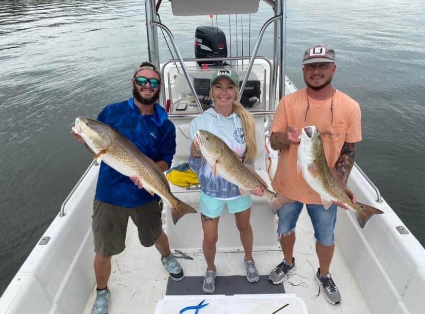 Three anglers proudly display their catch on a boat at Salty Dog Fishing Charters-Johns Pass-Treasure Island.