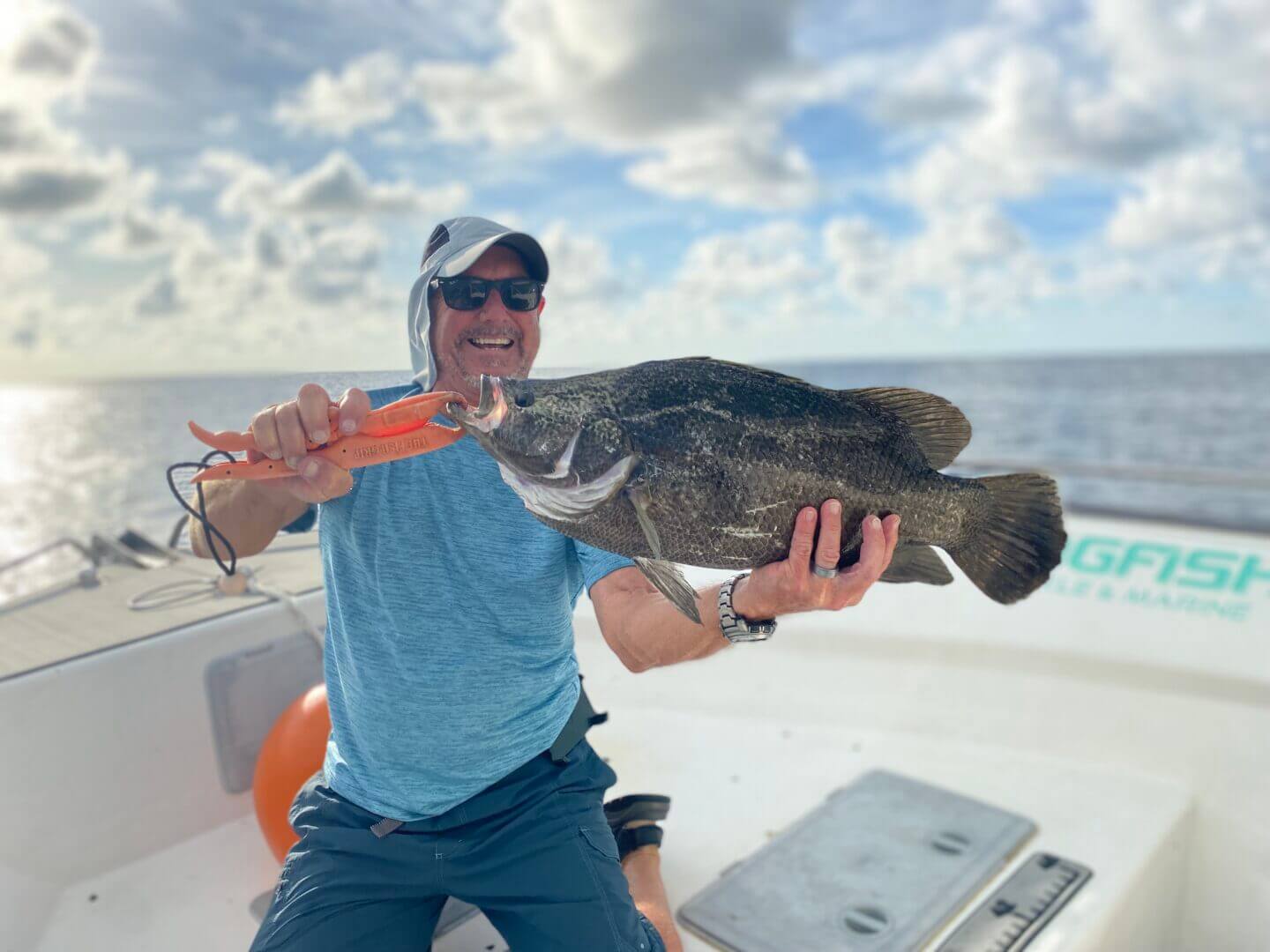 Man proudly holds a large fish on a boat with ocean backdrop, only at Salty Dog Fishing Charters-Johns Pass-Treasure Island.