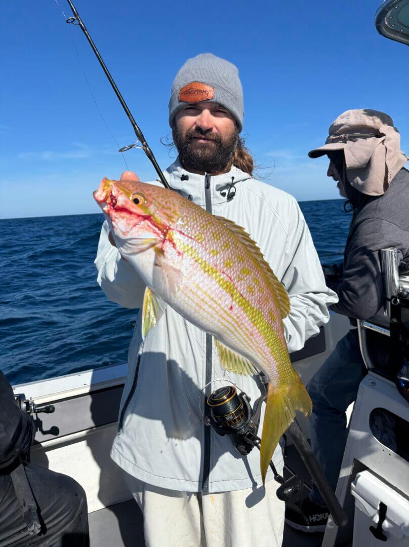 Angler holding a freshly caught fish on a boat, only available at Salty Dog Fishing Charters-Johns Pass-Treasure Island.