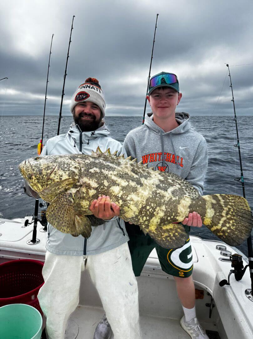 Two anglers holding a large fish on a boat, showcasing their catch with Salty Dog Fishing Charters-Johns Pass-Treasure Island.