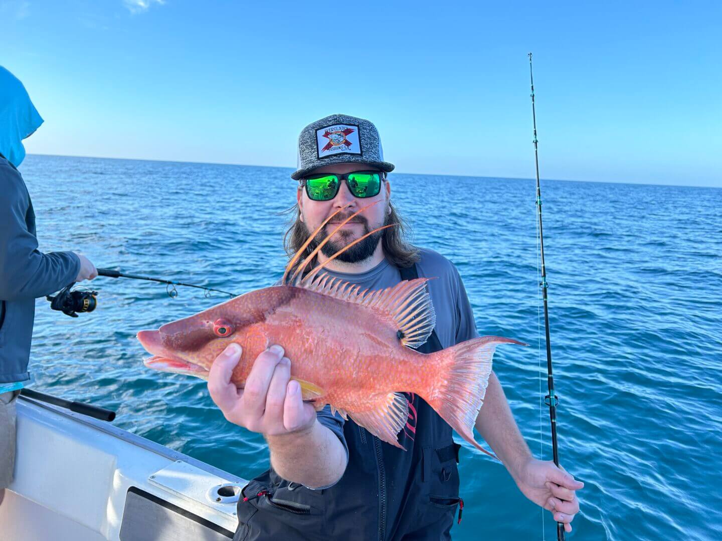 Angler holding a vibrant fish on a sunny day at sea, only with Salty Dog Fishing Charters-Johns Pass-Treasure Island.
