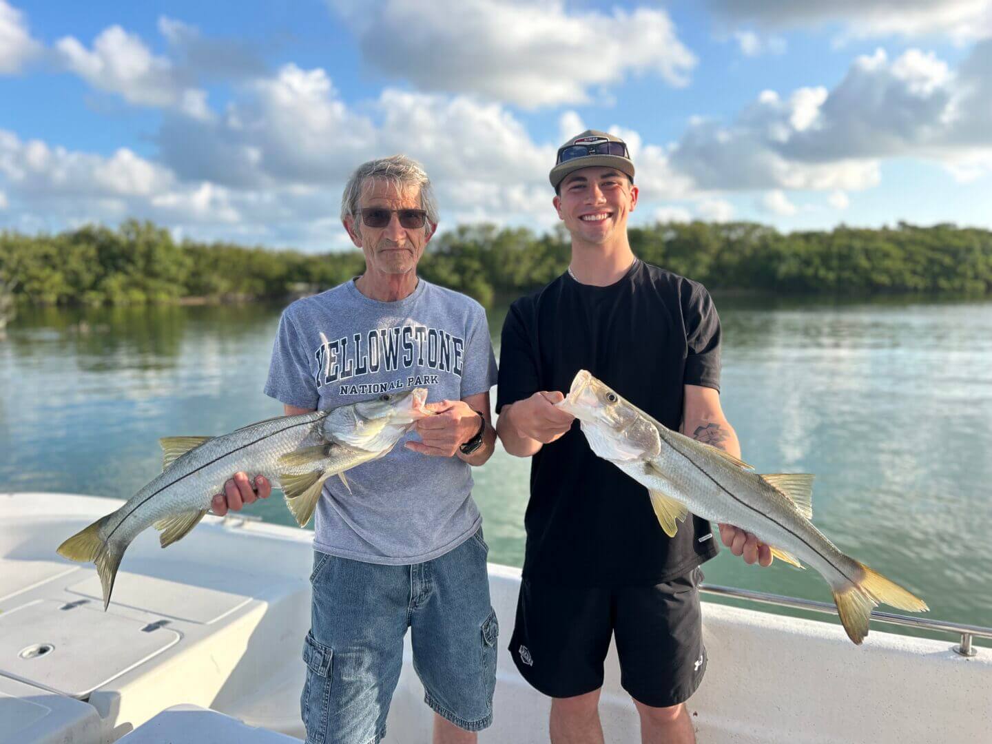 Two happy anglers holding snook aboard a boat, only available at Salty Dog Fishing Charters-Johns Pass-Treasure Island.