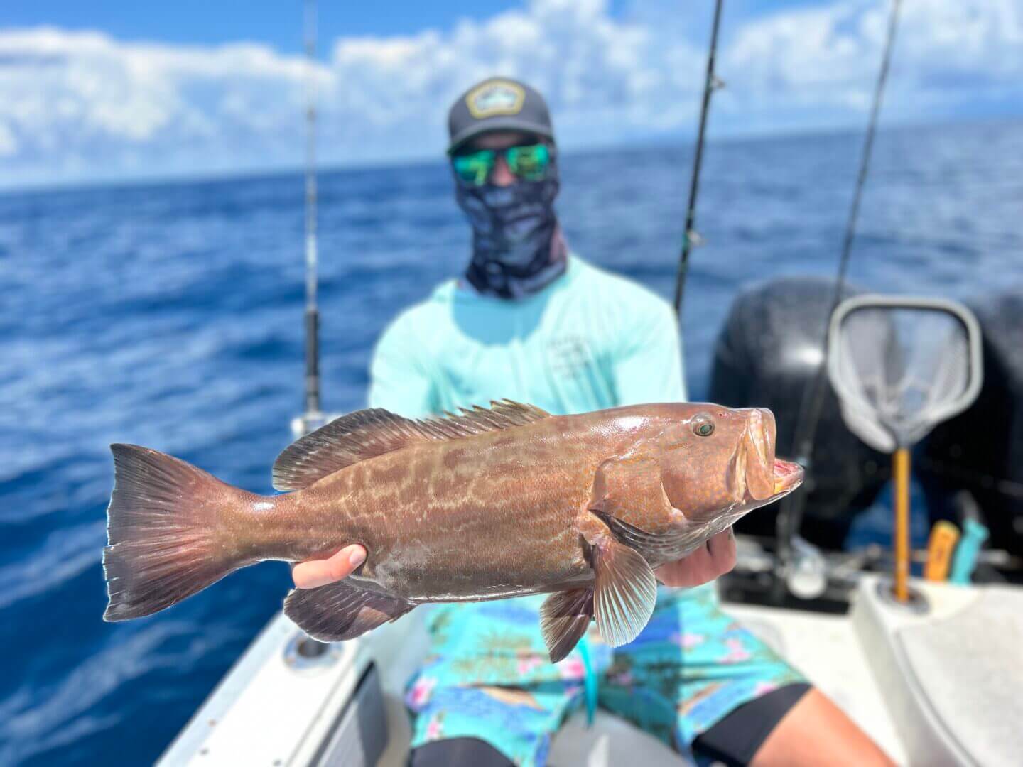 Man holding a freshly caught fish on a boat, only available at Salty Dog Fishing Charters-Johns Pass-Treasure Island.